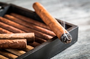 Burning cigar with smoke on old humidor